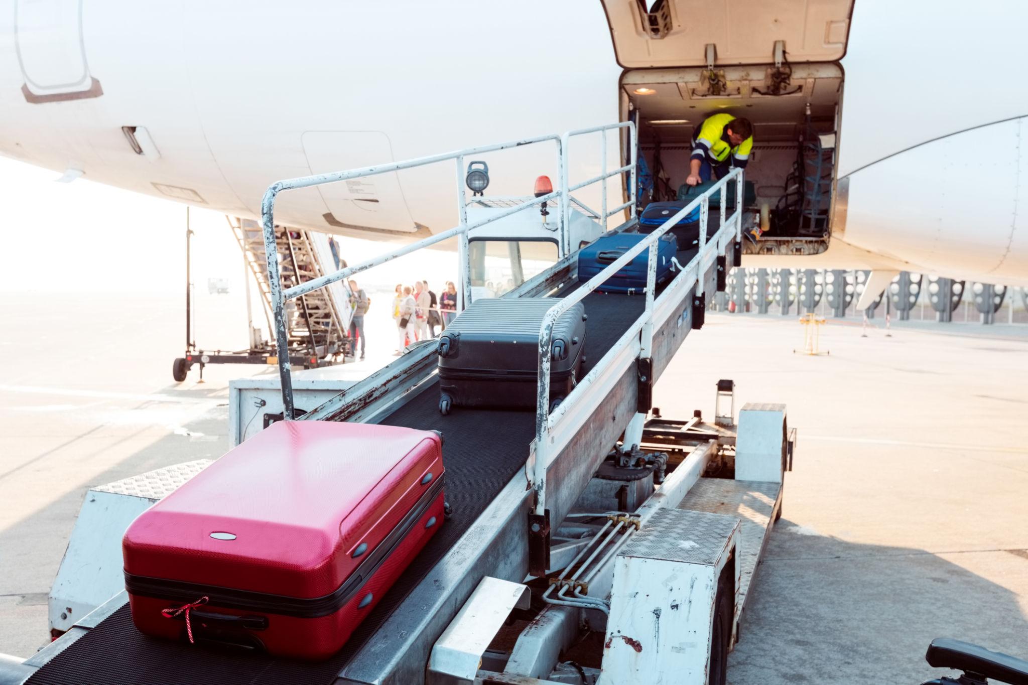 Airport ground staff performing baggage handling responsibilities and managing passenger luggage operations.